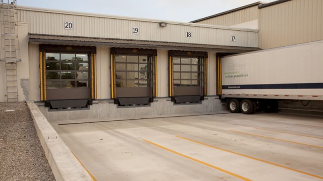 Three closed commercial garage doors with glass panels at truck bay.